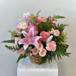 Pink lilies and roses arranged in a woven basket