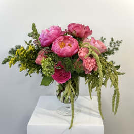 Pink peonies and roses arranged in a glass vase