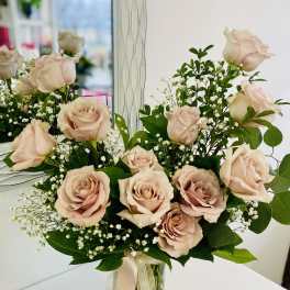 Tall vase of soft blush roses with baby's breath and trailing ivory ribbons