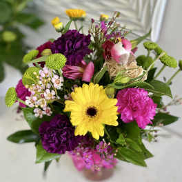 Mixed bouquet with yellow gerbera, purple carnations, and a small bird decoration
