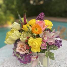 Colorful bouquet of roses, ranunculus, tulips, and orchids in a vase