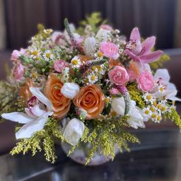 Mixed bouquet of pink, orange, and white flowers in a vase