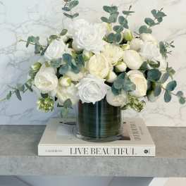 White roses and cream blooms in a glass vase with eucalyptus