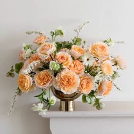 Peach and white roses arranged in a gold vase