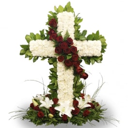 Floral cross arrangement with white flowers, red roses, and lilies
