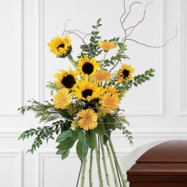 Sunflower funeral spray beside a wooden casket