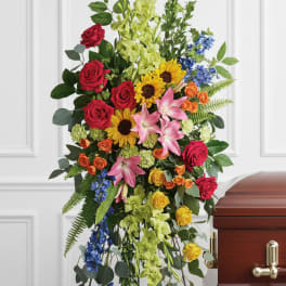 Tall standing floral spray with red roses, lilies, and blue accents