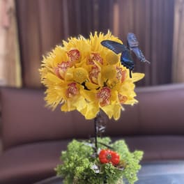 Yellow floral arrangement in a small pot with a blue butterfly accent