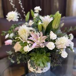 White and pale pink flowers arranged in a white vase