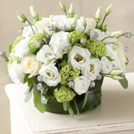 White roses and lisianthus arranged in a low round box