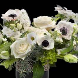 White roses and anemones arranged in a dark vase