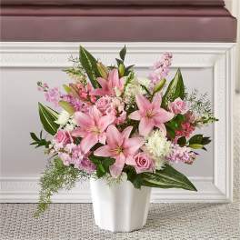 Pink lilies and roses arranged in a white vase