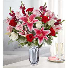 Bouquet of pink lilies and red and white roses in a glass vase