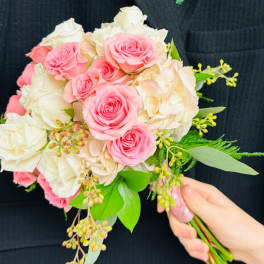 Pink and white rose bouquet with greenery, plus a matching boutonniere on a dark suit