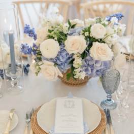 White and pale blue floral centerpiece on a table set for a formal event
