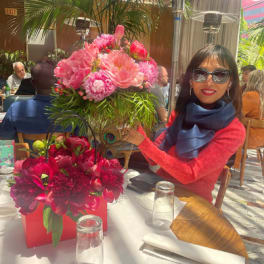 Two pink floral arrangements in red containers on a dining table