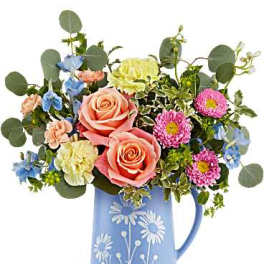 Mixed bouquet in a blue pitcher vase with pink roses and colorful blooms