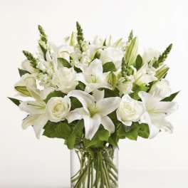 White lilies and roses arranged in a clear glass vase