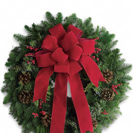 Evergreen wreath with a large red bow, pinecones, and red berries