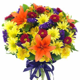 Bright bouquet of orange lilies, yellow daisies, and mixed flowers in a glass vase with purple ribbon