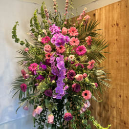 Tall floral arrangement with pink and purple blooms in a stand