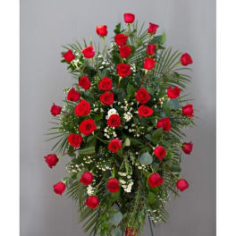 Standing spray of red roses with greenery on a metal easel