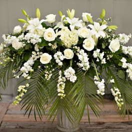 White floral arrangement with roses and lilies in a clear vase