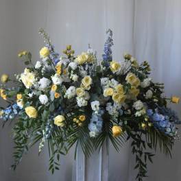 Large floral spray with yellow roses, white blooms, and blue flowers