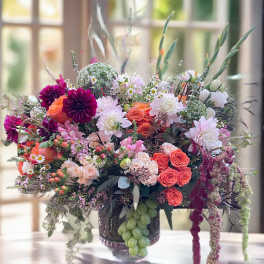 Large mixed bouquet in a glass vase with pink, orange, and white flowers