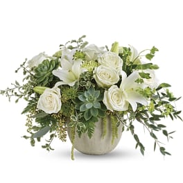 White roses and lilies arranged with succulents in a round vase