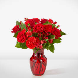 Red roses and carnations in a red glass vase