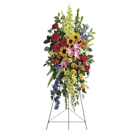 Standing floral spray with roses, lilies, sunflowers, and blue delphinium