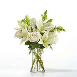 White lilies and roses arranged in a clear glass vase