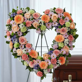 Heart-shaped floral spray on an easel beside a casket