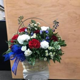 Basket arrangement of red, white, and blue carnations on a pedestal