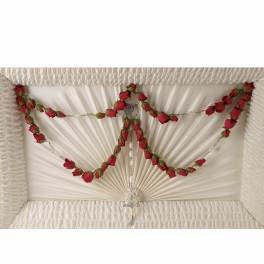 White casket with red rose garlands and a cross pendant