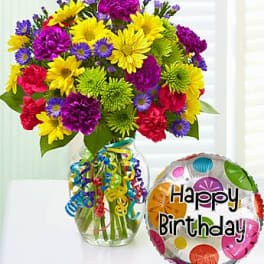 Bright mixed bouquet in a clear vase with curling ribbons and a colorful Happy Birthday balloon