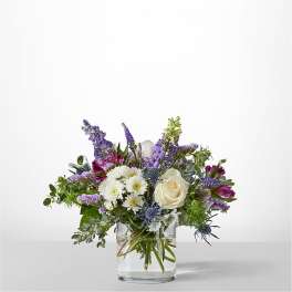 Mixed bouquet of white and purple flowers in a clear glass vase