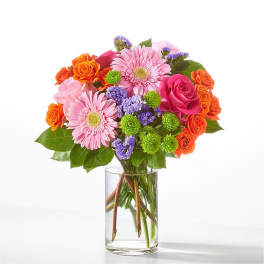 Mixed bouquet of pink, orange, and purple flowers in a clear glass vase