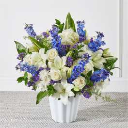 White lilies and roses with blue and purple flowers in a white vase