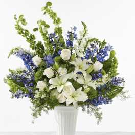 White lilies and roses with blue flowers in a white vase