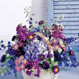 Basket of purple and blue mixed flowers with a handle