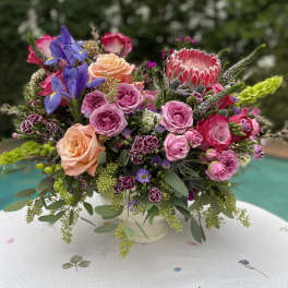 Colorful mixed flower arrangement in a white vase on a patterned tablecloth