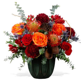 Red and orange floral arrangement in a dark vase