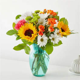Bouquet of sunflowers, daisies, and orange roses in a blue glass vase