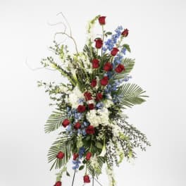 Tall standing floral spray with red roses, white blooms, and blue flowers