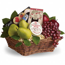 Wicker gift basket filled with pears, red grapes, apples, cheese, crackers, and gourmet treats