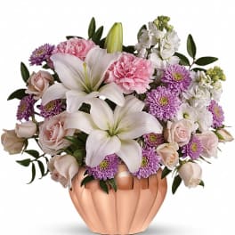 Pastel arrangement of lilies, roses, carnations, and mums in a copper bowl vase