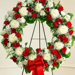 Standing wreath of red roses and white mums with a red bow on a metal easel