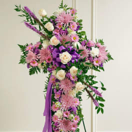 Standing cross spray of pink and purple flowers with white roses on an easel
